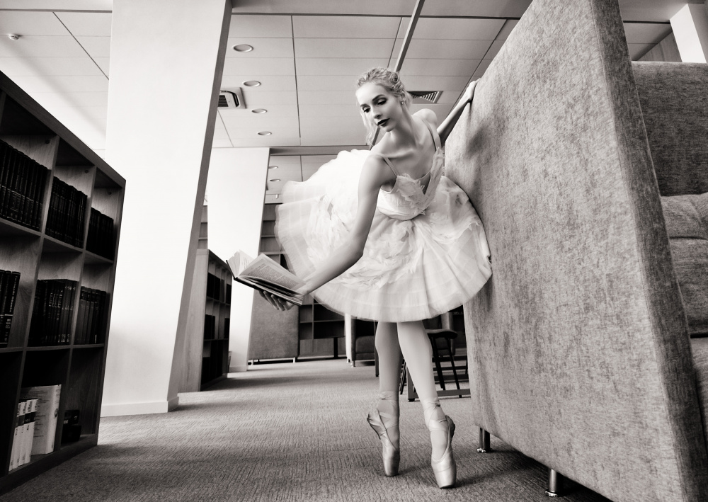 ballerina on pointe shoes in the library reads a book holding it up a Alexandr