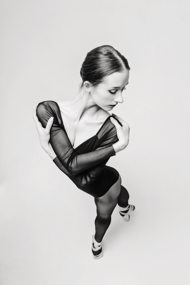 portrait of a ballerina in a black bodysuit top view standing with her arms  around her shoulders - Alexandr