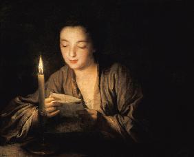Giovane donna che legge una lettera alla luce della candela