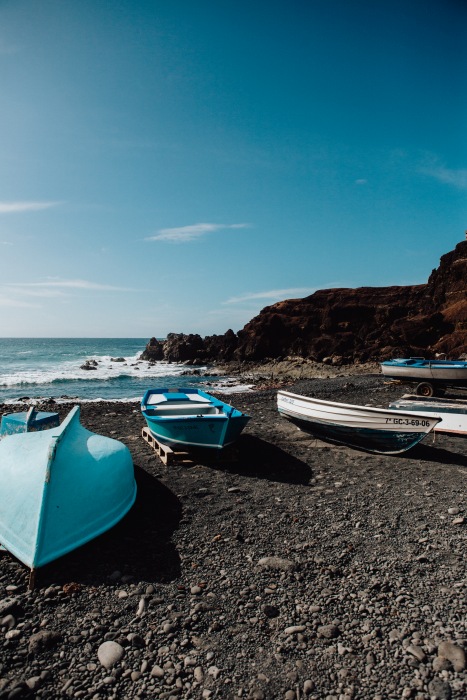 Blaue Boote auf schwarzem Vulkansstrand auf Lanzarote a Laura Nenz