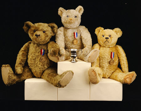Three Farnell Teddy Bears On A Medal Winners Plinth a 